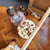 Blick von oben auf die Platte von Grapat "The Pendulum", auf die ein Mädchen geraden verschiedene Holzbausteine legt und versucht, dass das Gleichgewicht bestehen bleibt.