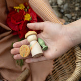 Eine Kinderhand hält drei bemalte Holzfiguren zum Spielen aus dem Überraschungsset Grapat Lucky Lucky 4.0.