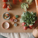 Kleine Spielmaterialien aus Holz, genial für die Puppenküche, wie Gemüse bemalt, aus dem Grapat Adventkalender 2025 liegen zwischen echtem Gemüse.