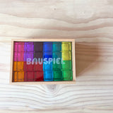 Alle 24 Stück der bunten Lichtbauquader Bausteine von Bauspiel aus Acryl sind im Holzkasten mit transparentem Deckel geschlichtet.