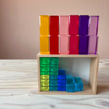 Blick auf die Holzkiste von Bauspiel: die grünen und blauen Lichtbauquader aus Acryl sind darin einsortiert, die roten, gelben und violetten auf dem Rand hochkant aufgestellt.