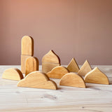 Zwölf "Funkeldächer" Holzbausteine von Bauspiel in verschiedenen Formen, mit Blick auf die Rückseite aus Holz sind auf dem Boden aufgestellt.