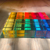 Eine Seitenansicht von einem Rechteck, das aus 5 x 4 transparenten, bunten Acrylbauklötzen der Firma Bauspiel in gelb, orange, rot, pink, grün und blau besteht.