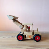 Der Fagus Radlader aus Holz zum Spielen für Kinder ab 3 Jahren von der Seite, im Führerhaus ist eine Spielfigur aus Holz.
