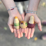 Die drei Holzspielfiguren "Familie Ooh La La" in den Handflächen eines Kindes liegend.