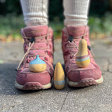 Die drei Holzspielfiguren "Familie Ooh La La" von Grapat stehen auf und zwischen den Stiefeln eines Kindes.