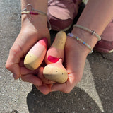 Ein Kind hält die drei Holzspielfiguren "Familie Yay" von Grapat.