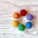 Filzbälle von Kokomoo in sechs Regenbogenfarben aufgelegt in einem Kreis.