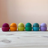 Filzbälle von Kokomoo in sechs verschiedenen erdigen Farben in den farblich passenden kleinen Holzschalen liegend.