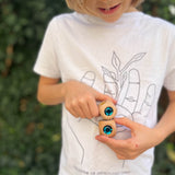 Ein Kind hält zwei Glitzerwürfel mit türkisen Glitzersteinen von Nic Toys aufeinander gestapelt in den Händen.