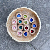 Dreizehn Glitzerwürfel in verschiedenen Farben von Nic Toys liegen in einem Körbchen.