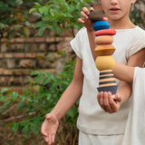 Ein Junge hält den die bunten gestapelten Grapat Serendipity Bausteine in einer Hand und balanciert diesen Stapelturm, während ein anderes Kind versucht noch einen Bauklotz oben drauf zu platzieren.