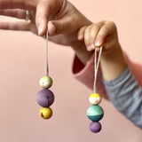 Hände halten zwei verschiedene Snow Buddy Anhänger von Grapat.