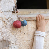 An einer alten Mauer hängen zwei Christbaumkugeln von Grapat Wish Balls.