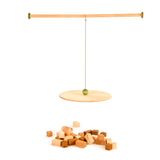 Das komplette Grapat "The Pendulum" Set: Holzstange, an einer Schnur mit Kugel montierte runde Holzplatte und verschieden große Holzbausteine in Quaderform.