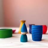 Eine Spielfigur "Grapat Tomtens" in blau steht neben dem blauen Grapat Pots Holzbecher.