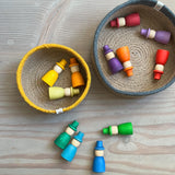 In zwei runden Jutekörben mit blauem und gelben Rand liegen Grapat Wizard Holzfiguren zum Spielen in verschiedenen Farben. Daneben liegen auch noch vier Wizards in blau und grün.