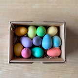 Grapat "Happy Eggs" bunte Eier aus Holz in 12 verschiedenen frühlingshaften Farben liegen in ihrer Kartonverpackung.