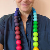 Die 3cm Holzkugeln von Grimms hängen farblich sortiert asl Kette um den Hals einer Frau.