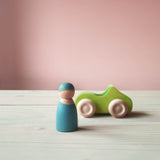 Grimms Holzauto grün, daneben eine blaue Spielfigur aus Holz.