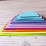 Die 11 halbkreisförmigen Bauplatten von Grimms in pastelligen Regenbogenfarben liegen übereinander gestapelt, die geraden Kanten sind zu sehen.