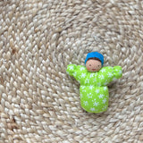 Das kleine Grimms Waldorf-Püppchen Baby Leo in grün mit blauer Haube.