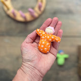 Das kleine Grimms Püppchen Baby Mia in orange liegt in einer Handfläche.