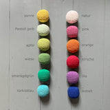 12 Häkelbälle von Kokomoo aufgelegt, daneben stehen jeweils die Farbbezeichnungen.