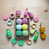 6 Häkelbälle für freies Spiel in sorbet-Farben von Kokomoo in einer Kartonschachtel, rundherum liegt das Holzspielzeug Set "Freunde im Zauberwald" von Grapat.