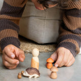 Ein Kind spielt mit der Spielfigur, den beiden Holzpilzen und dem Igel aus dem Set "Hello Autumn" von Grapat und Ostheimer.