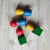 Schrauben und Muttern aus Holz von Nic Toys in den Farben rot, gelb, grün und blau bunt zusammen geschraubt.