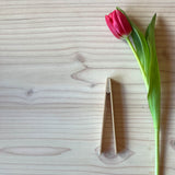 Die kleine Holzzange von Grapat liegt neben einer pink farbenen Tulpe.