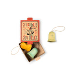 Die Christbaumanhänger "Jingle Joy Bell" von Grapat, zwei in der geöffneten Verpackung, eine Weihnachtsglocke aus Holz daneben.