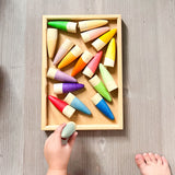 Die Grapat "Sticks" Holzfiguren zum Spielen liegen wild durcheinander in einem Holztablett. Eine Kinderhand hält eine Spielfigur.