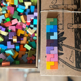Drausicht auf kleine bunte L-förmige Bausteine, die in einer bunten Reihe aneinandergelegt sind.