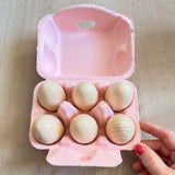 6 Holzeier in einem offenem, rosa Eierkarton