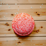 Draufsicht auf den rot-weiß geprenkelten Confetti Stapelstein Red& Blush auf einem Holzbretterboden liegend.