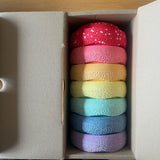6 kleine Steine des Stapelstein MINI Regenbogen Set Pastell gestapelt im Karton, ganz oben ein siebter Mini-Stein, nämlich Confetti Red&Blush.