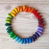 Die 36 Stück Grapat "Rainbow Snowflakes" Mandalasteine in Schneeflocken-Form farblich sortiert in einem Kreis aufgelegt.