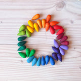 Die 36 Stück Grapat "Rainbow Snowflakes" Mandalasteine in Schneeflocken-Form farblich sortiert in einem kleinen Kreis aufgelegt.