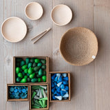 Das Mandala Set Blau-Grün MITTEL von Kokomoo aufgelegt, die Mandala Steine in blau und grün liegen in ihren vier Verpackungsboxen, daneben die Holzteller, der Jutekorb und die kleine Holzzange.