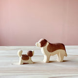 Eine kleiner Bernhardiner sieht zum großem Bernhardiner auf. Beide sind Spielfiguren aus Holz von Ostheimer.