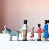 Fünf Ostheimer Holzfiguren zum Spielen stehen in einer Reihe hintereinander und schauen nach links. Ganz vorn der graue Esel, dahinter der dunkle Papa, dann Heidi, danach der Sohn und als letzte in der Reihe die dunkle Mutter.