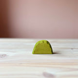 Hellgrünes stehendes Holzstück mit gerunderter Oberseite, ca. 5cm hoch. Das ist das hellgrüne Gebüsch von Ostheimer, eine beliebte Holzfigur zum Spielen für Kinder.