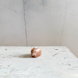 Das kleine Ostheimer Häschen sitzt auf einem hellen Holzuntergrund.