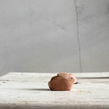 Die Ostheimer Bauernhoffigur Hase klein sitzt auf einem hellen Holzuntergrund und schaut nach rechts.