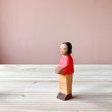 Die Ostheimer Spielfigur Sohn aus Holz steht auf einer Holzplatte und schaut schräg nach vorne.