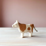 Ostheimer Kuh Spielfigur aus Holz mit braunen Flecken, steht mit erhobenem Kopf und Blick nach links.