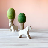 Im Vordergrund steht das Ostheimer weiße Lamm laufend. Im Hintergrund 2 Filzbäume Sommer und Frühling und davor ein weißes Schaf