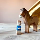 Die Spielfigur Mo, ein kleiner Zwerg von Ostheimer, rechts neben ihm steht braunes Holzpferd von Ostheimer.